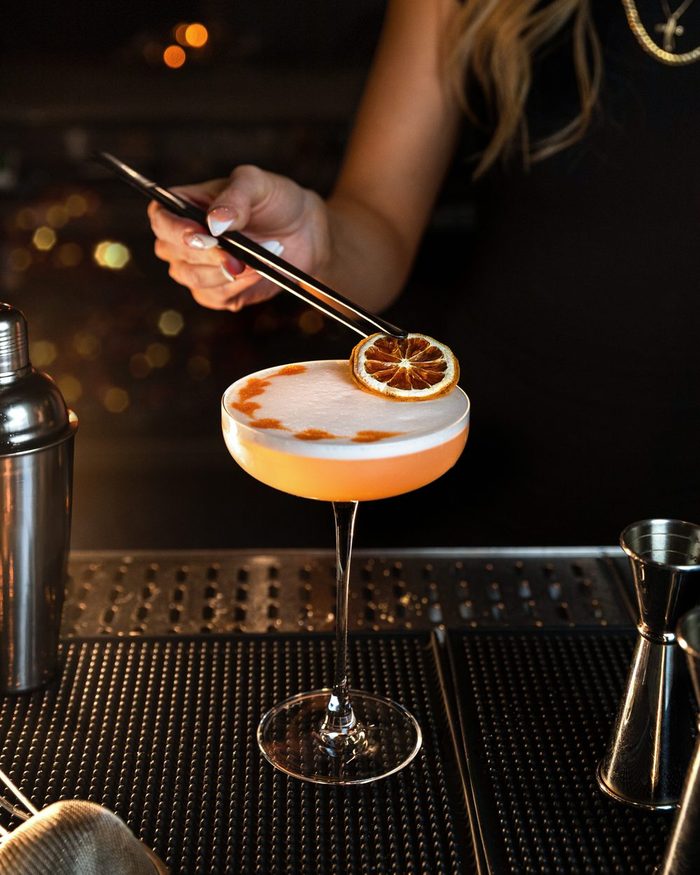 Bartender garnishing a signature coupe cocktail with a dried citrus wheel at Beacon Social House