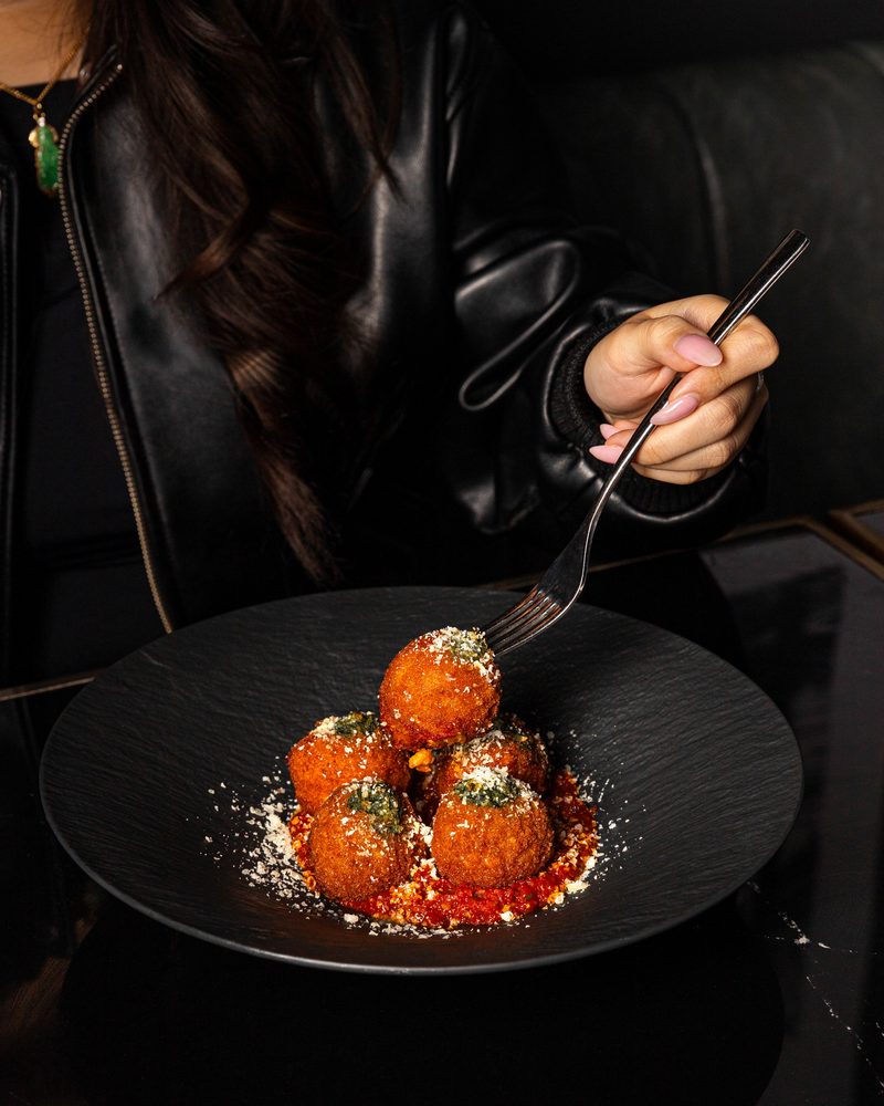 Arancini with parmesan and basil over spiced tomato, served at the table