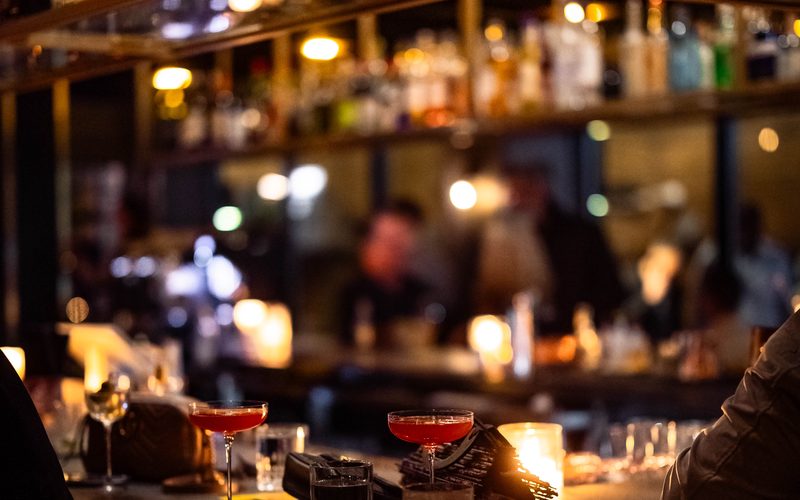 Cocktails on the marble bar top, candlelight and the backlit whisky shelves behind