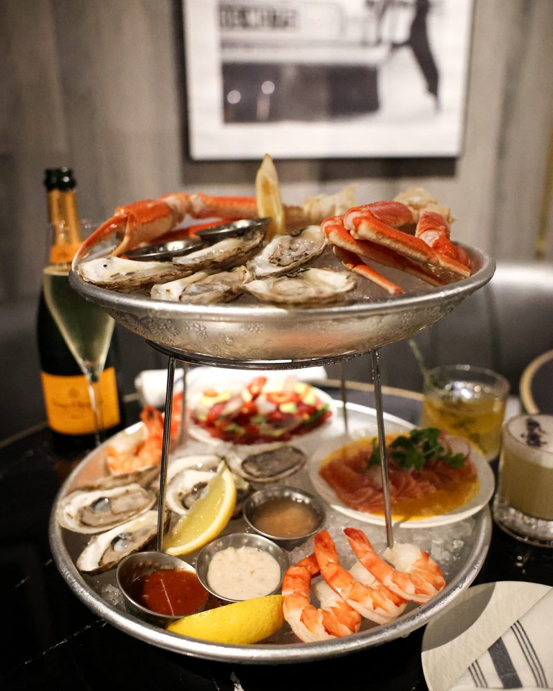 A two-tier seafood tower &mdash; crab legs, oysters, jumbo shrimp, tuna tartare and salmon crudo, served with champagne