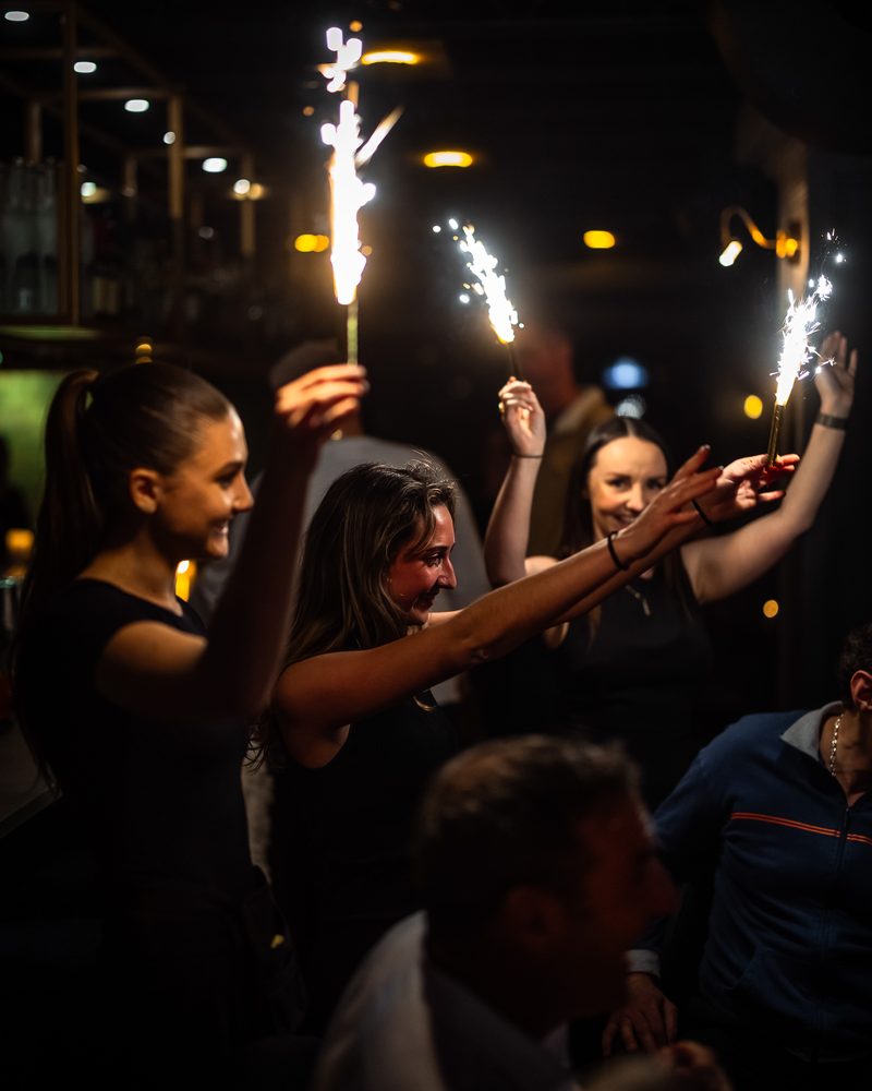 Guests raising sparklers at the bar on a Friday night at Beacon Social House