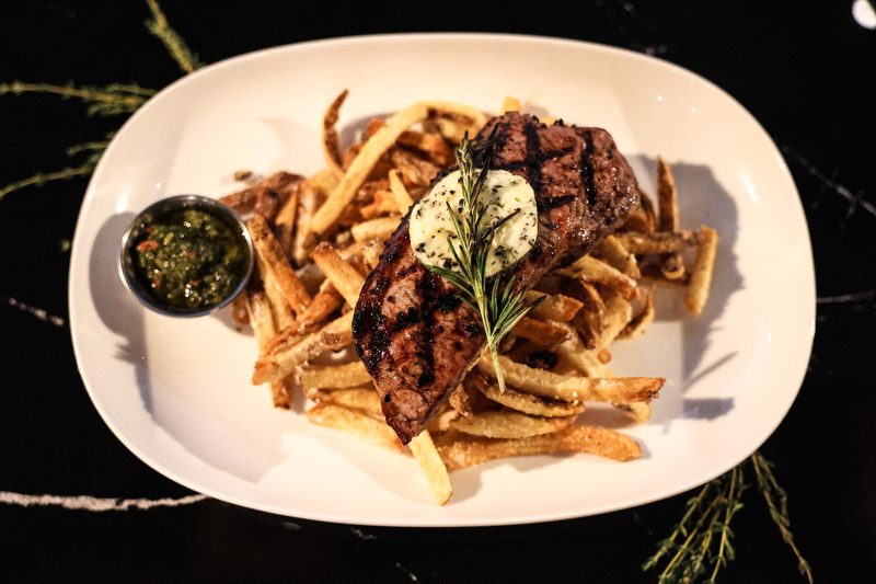 Grilled striploin with rosemary butter, chimichurri and truffle fries on black marble